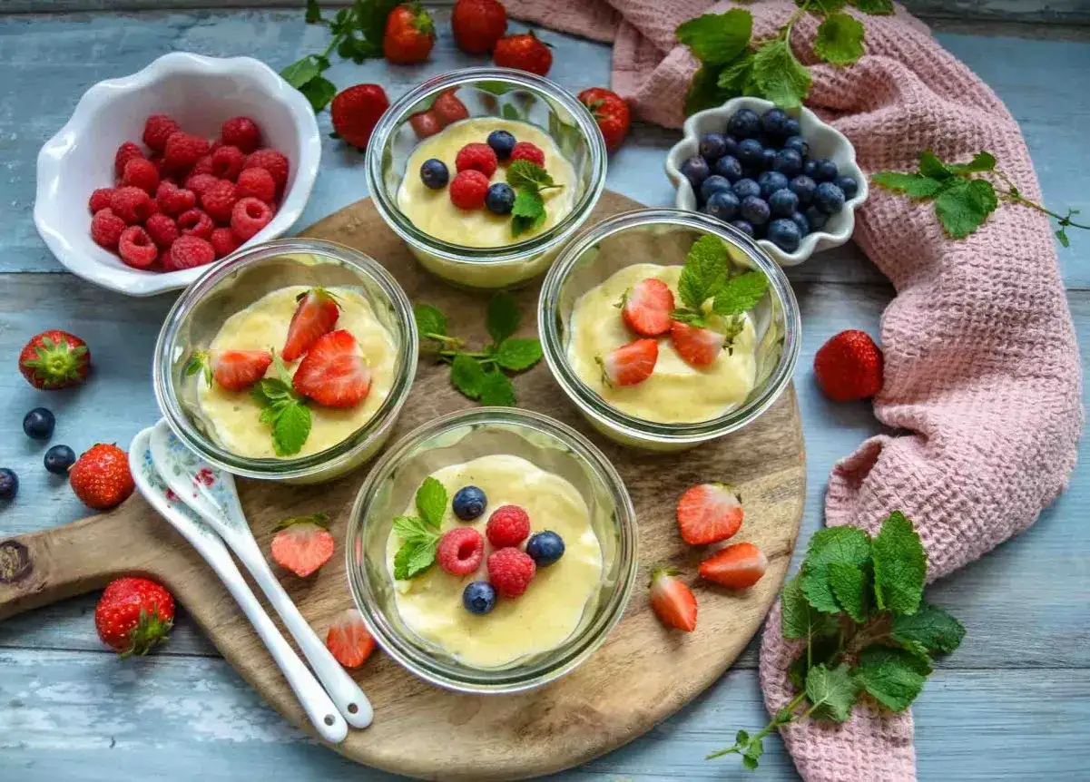 Vier Gläschen mit selbst gemachtem Pudding, garniert mit frischen Beeren und Minze. Ein Genuss, der zum Nachmachen einlädt.