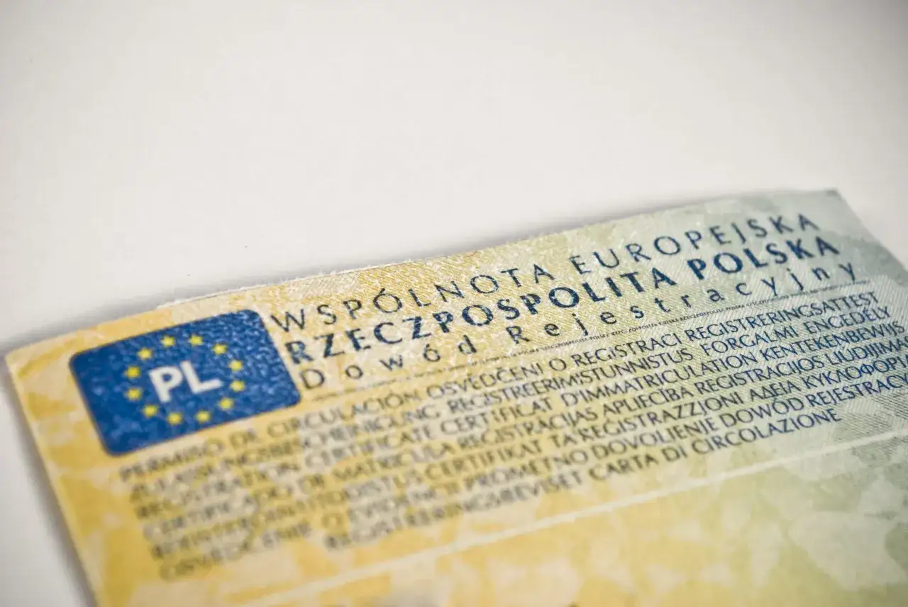 Dowód rejestracyjny pojazdu, niezbędny do ubezpieczenia samochodu, z flagą PL i tekstem w wielu językach.