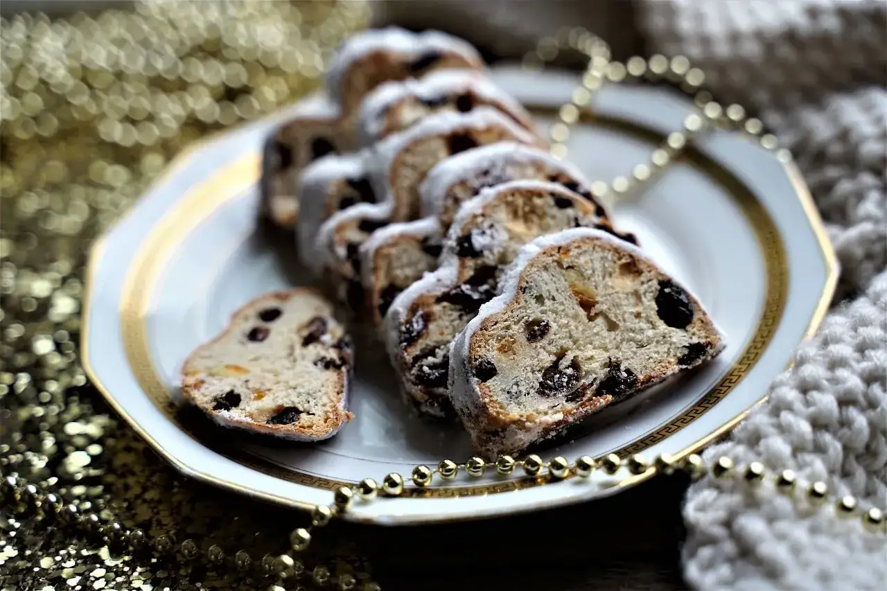 Tranches de stollen, un g&acirc;teau de No&euml;l traditionnel aux fruits secs, saupoudr&eacute; de sucre glace, dispos&eacute;es sur une assiette orn&eacute;e.