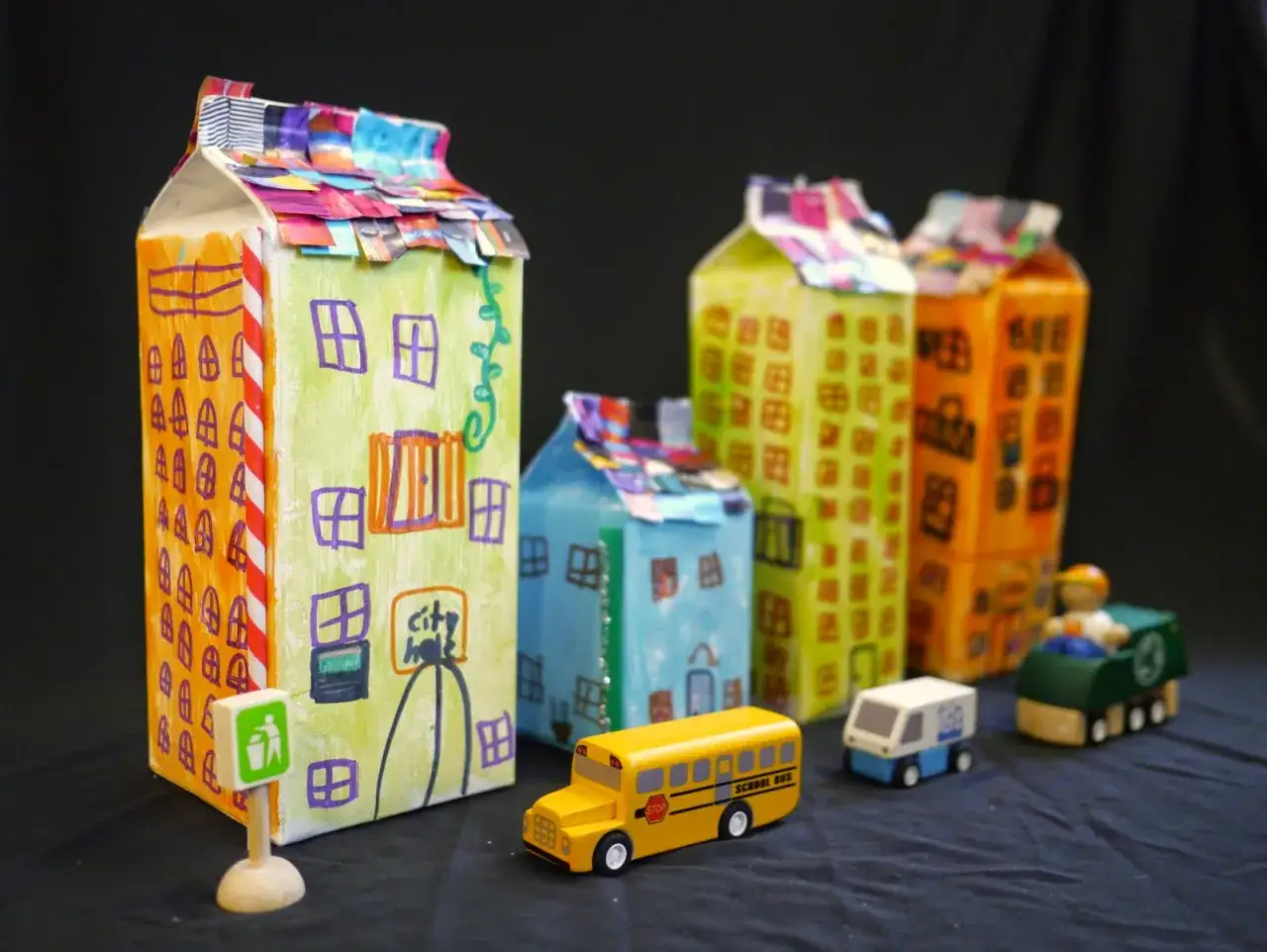 Kreative Stadt aus Milchkartons: Ein Haus aus Milchkarton basteln ist eine tolle Idee! Hier sind bunte H&auml;user mit Spielzeugautos und einem M&uuml;llmann.