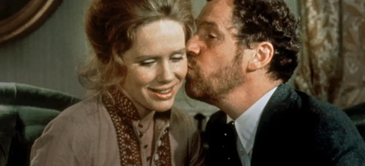En man kysser en kvinna på kinden i en scen från en svensk dramafilm.