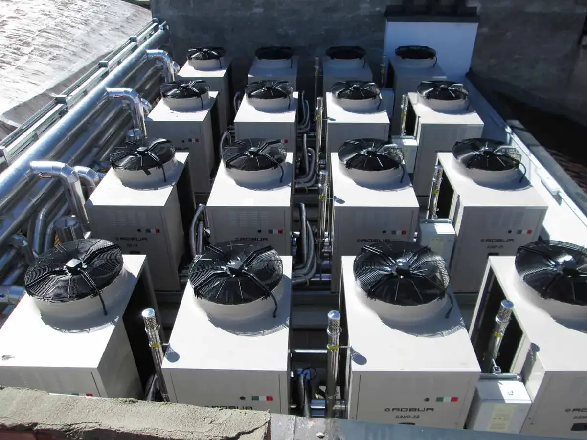 Un insieme di pompe di calore sul tetto, con ventole nere e tubature metalliche, per un efficiente sistema di climatizzazione.