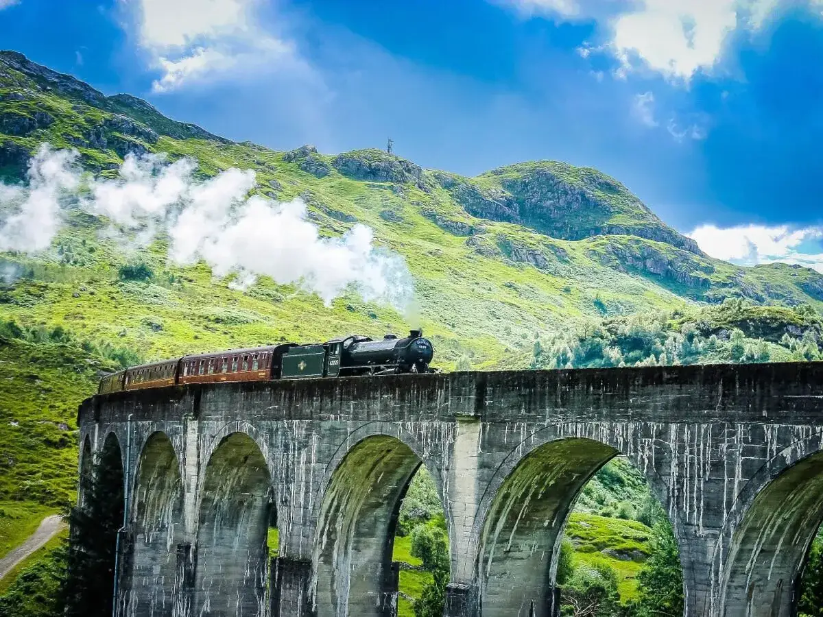 Dampflok fährt über das Glenfinnan Viadukt, ein magischer Moment auf der Reise von Edinburgh in die Highlands.