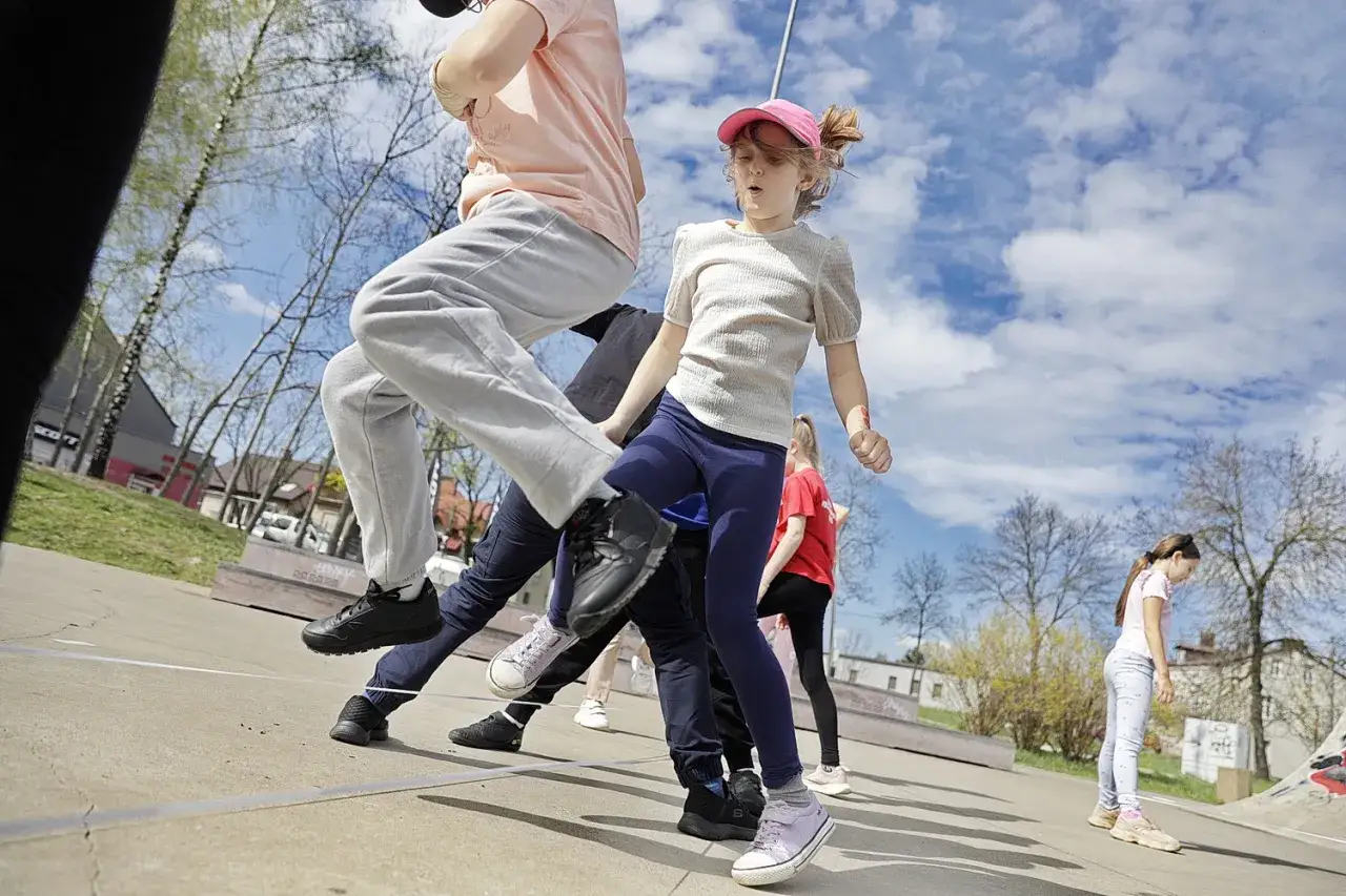 Dzień dziecka zabawy na powietrzu. Dzieci skaczą przez gumę na skateparku, ciesząc się wiosennym dniem.