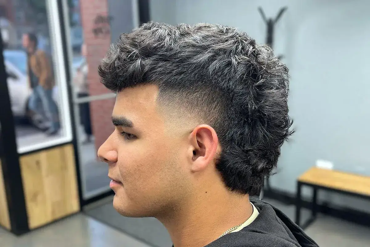 Joven con un moderno mullet, cabello rizado y degradado en los laterales.