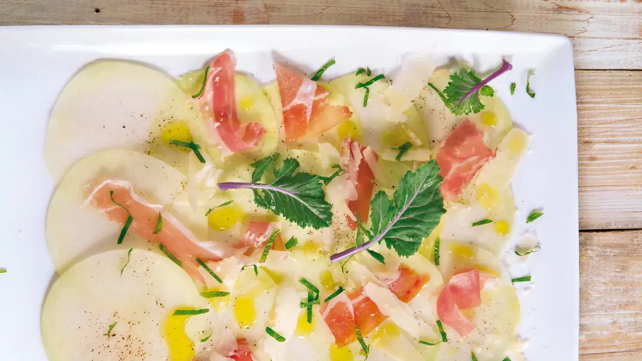 Kohlrabi Carpaccio mit hauchdünnen Kohlrabischeiben, Parmaschinken, Parmesan, Olivenöl und frischen Kräutern.