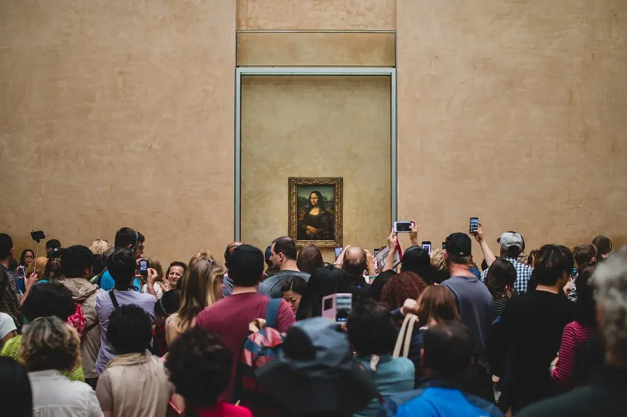Eine Menschenmenge bestaunt die Mona Lisa im Louvre. Die Frage, wem die Mona Lisa gehört, beschäftigt viele Besucher.