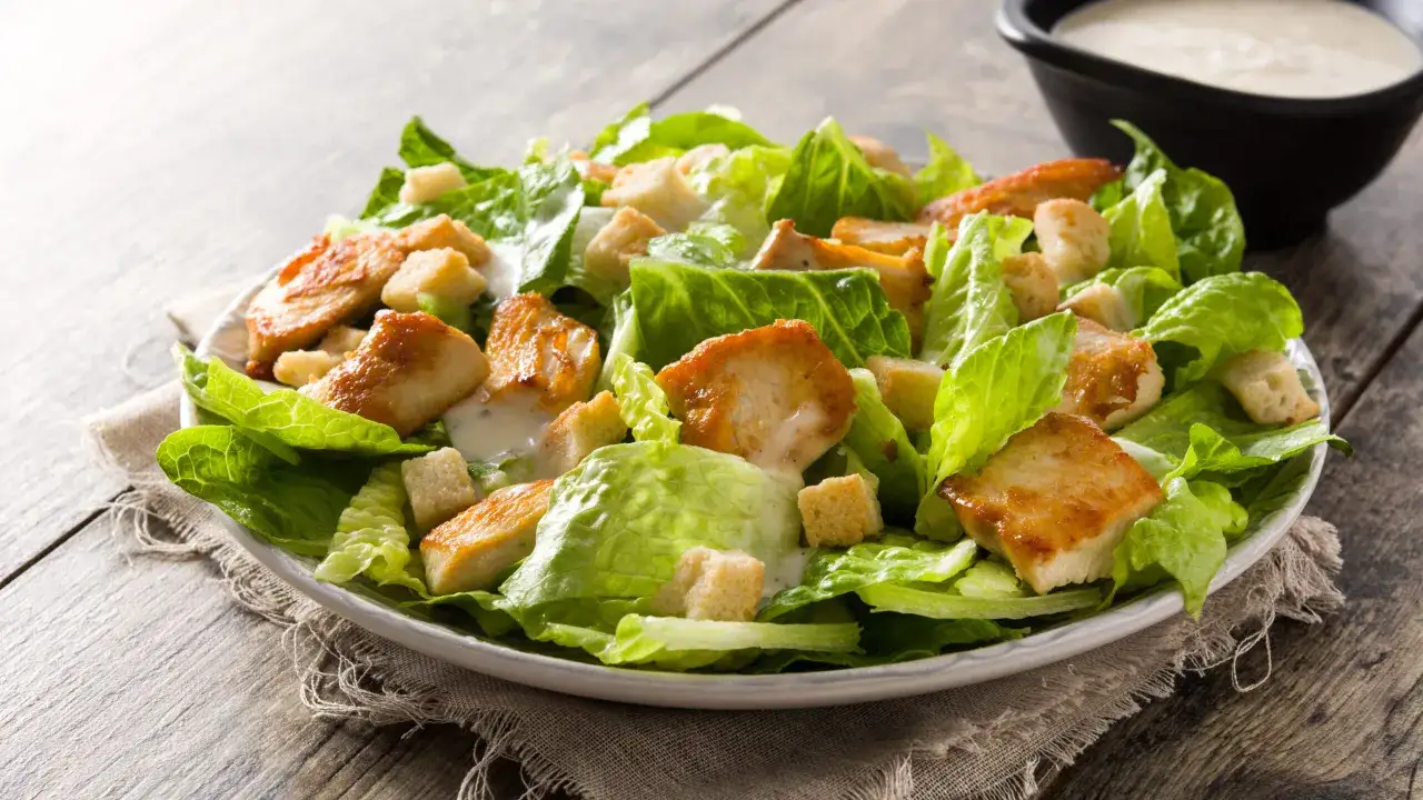 En härlig caesarsallad med krispig romansallad, saftiga kycklingbitar och krutonger. Perfekt för ett snabbt caesarsallad recept.