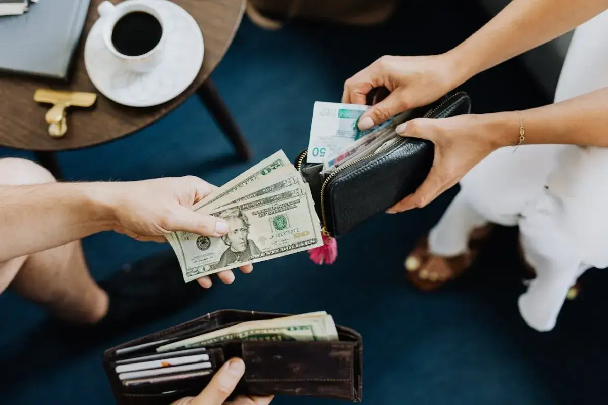 Dwie osoby wymieniają pieniądze. Jedna daje dolary, druga wkłada do portfela banknoty, być może sprawdzając turcja waluta kurs.