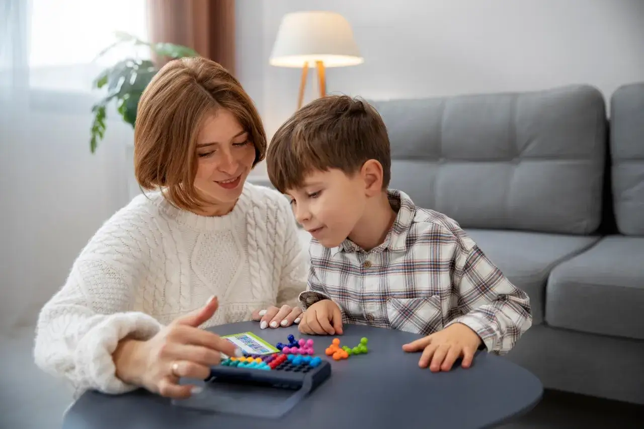 Une mère et son fils jouent à un jeu de réflexion coloré, le **wppsi iv** est un excellent outil pour évaluer les capacités cognitives.