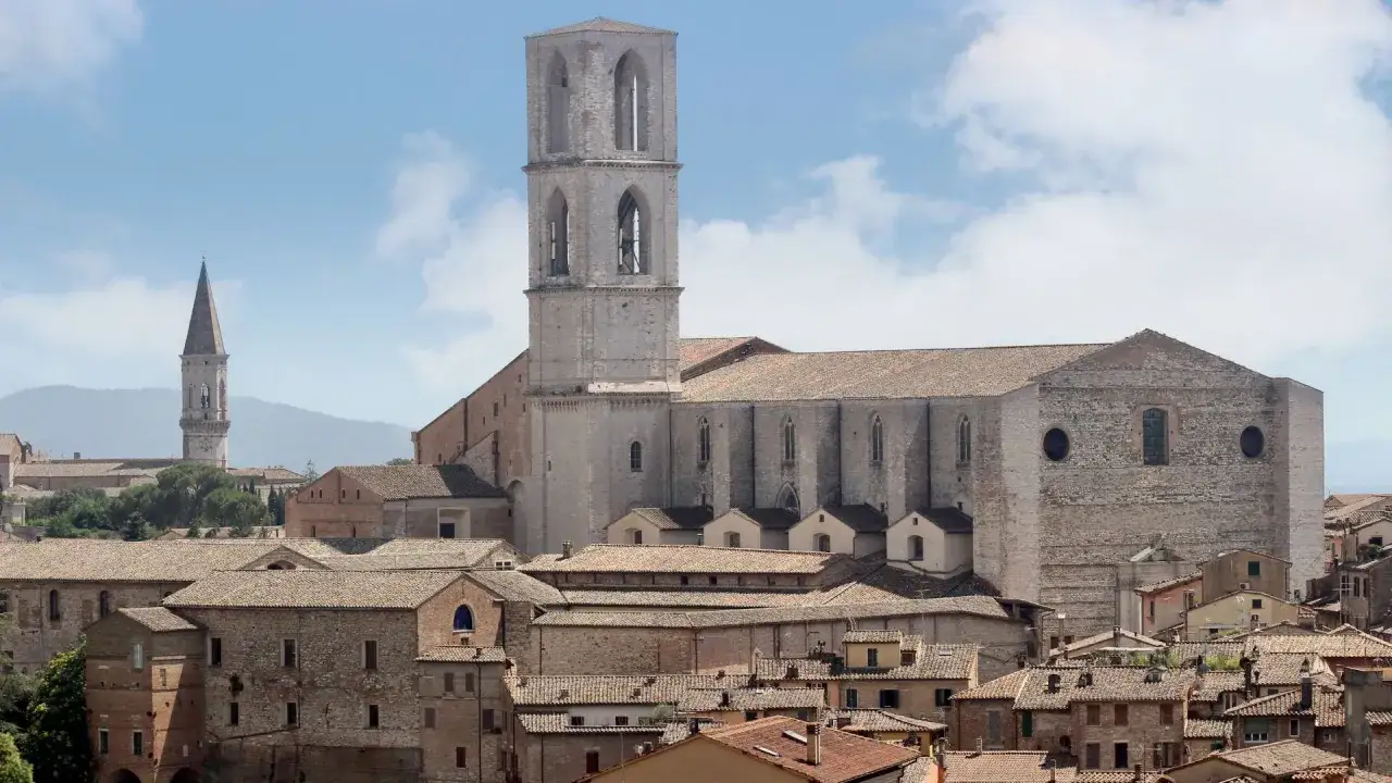 Perugia zwiedzanie: imponująca katedra z wieżą i inne zabytkowe budynki na tle wzg&oacute;rz.