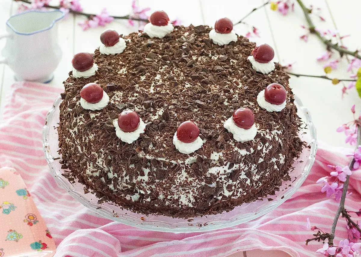 Tarta Selva Negra, cubierta de virutas de chocolate y coronada con cerezas y nata. ¡Un postre irresistible!