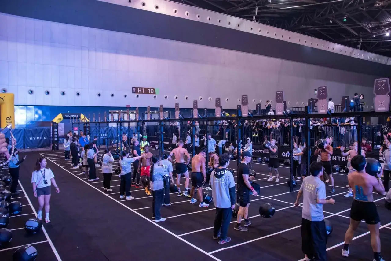 Teilnehmer bereiten sich auf einen Hyrox-Wettkampf vor, mit Wall Balls und anderen Trainingsgeräten.