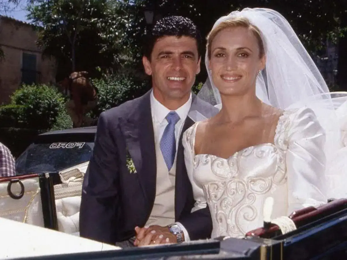 Novia sonriente junto a su esposo, un hombre elegante. Ella es una de las mujeres de toreros famosos, luciendo un vestido de novia de ensue&ntilde;o.