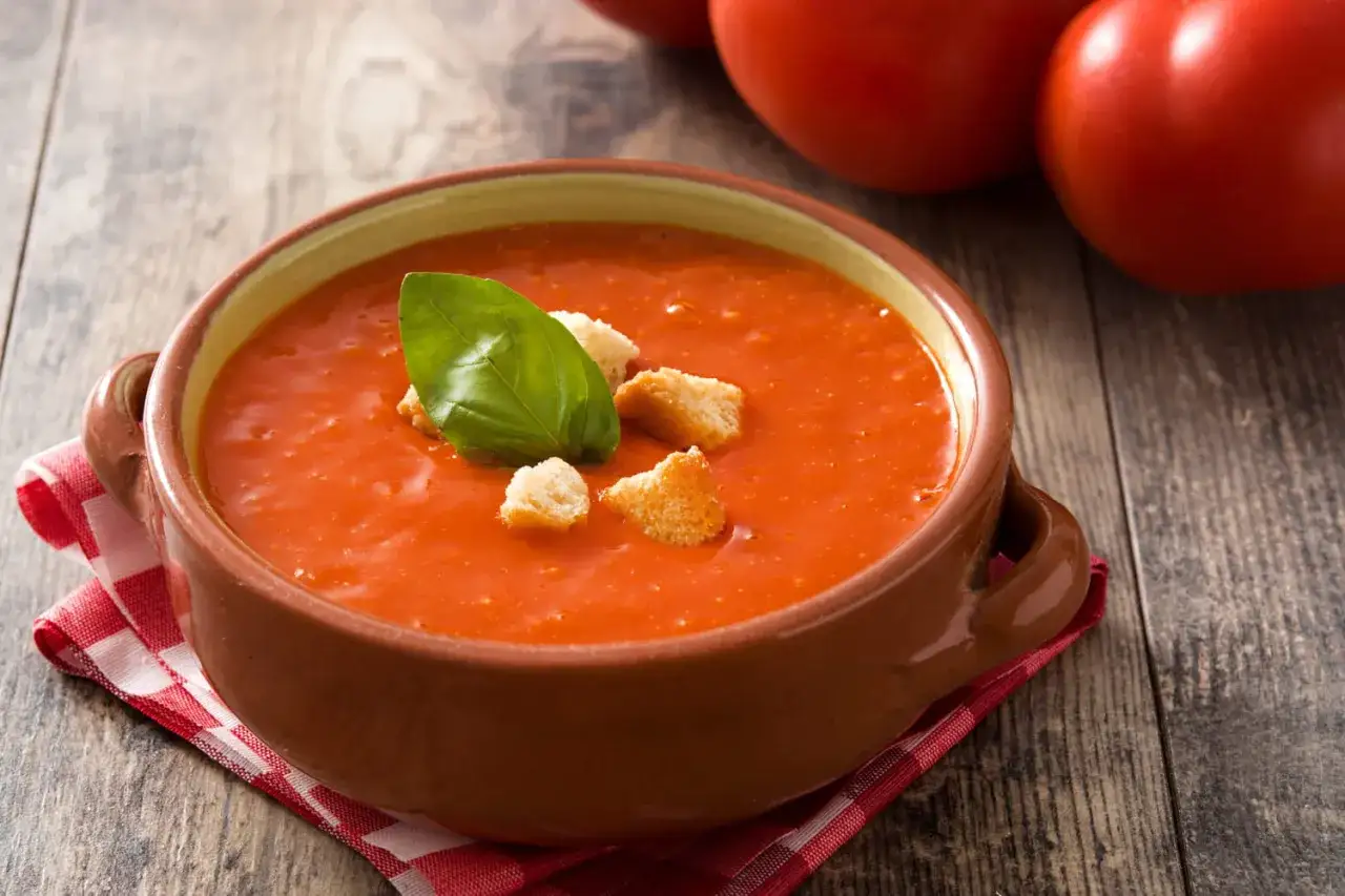 Soupe de tomates maison, garnie de croûtons et d'une feuille de basilic. Parfait pour savoir que faire avec des tomates trop mures.