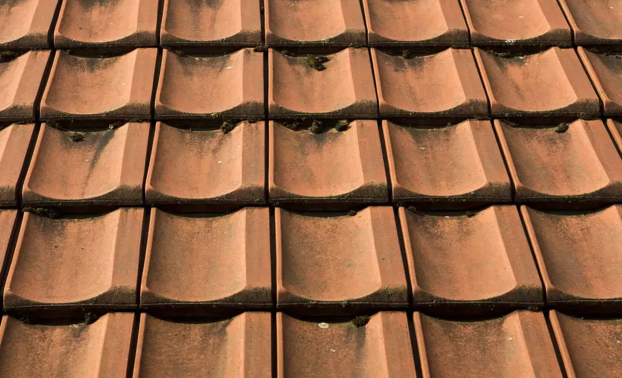 Czerwona dachówka ceramiczna, z widocznym mchem, idealna do obliczenia, jaka będzie dachówka ceramiczna cena za m2.