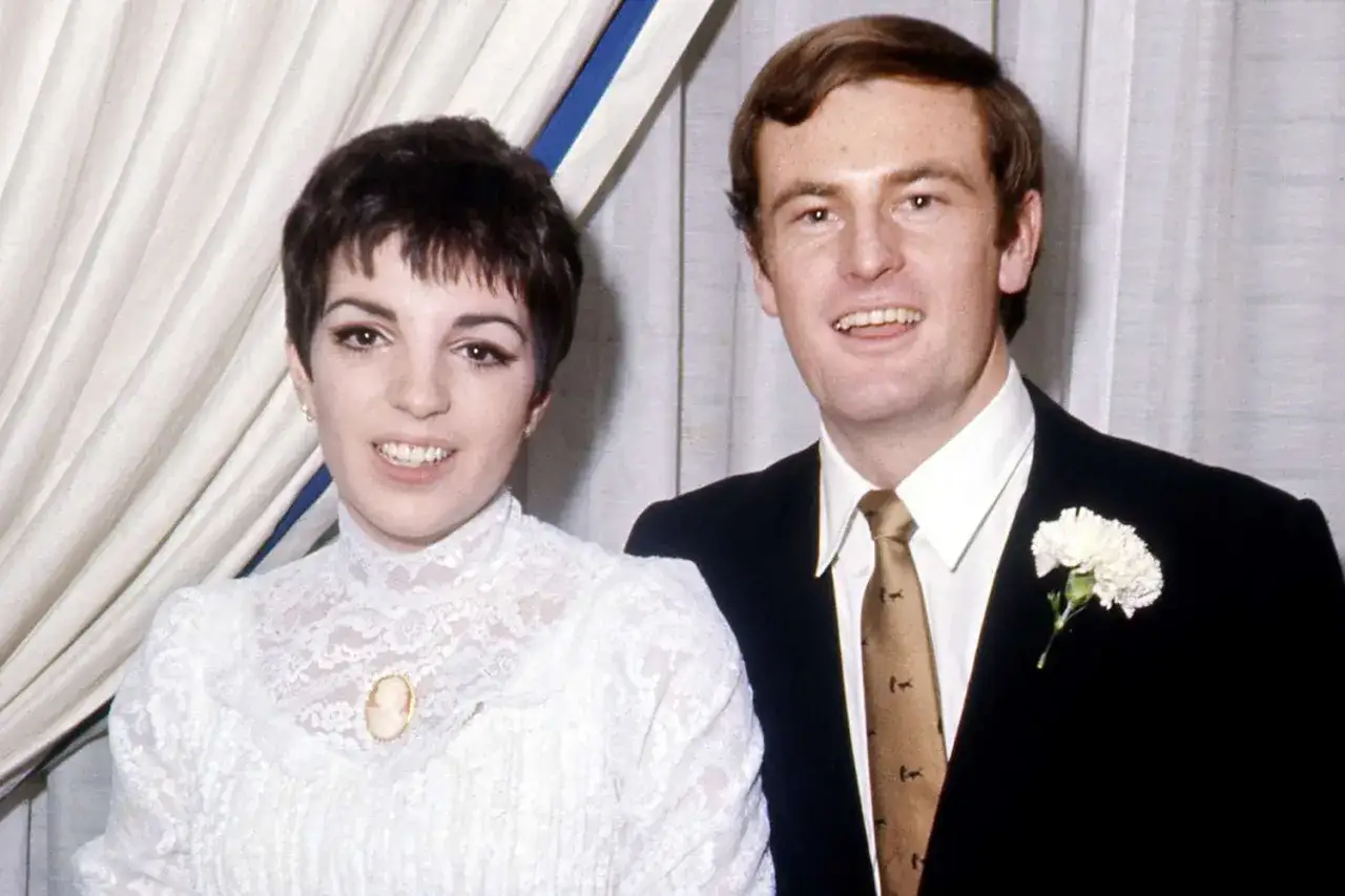 Liza Minnelli i hennes make, Peter Allen, ler mot kameran. Liza b&auml;r en vit spetskl&auml;nning med en brosch.