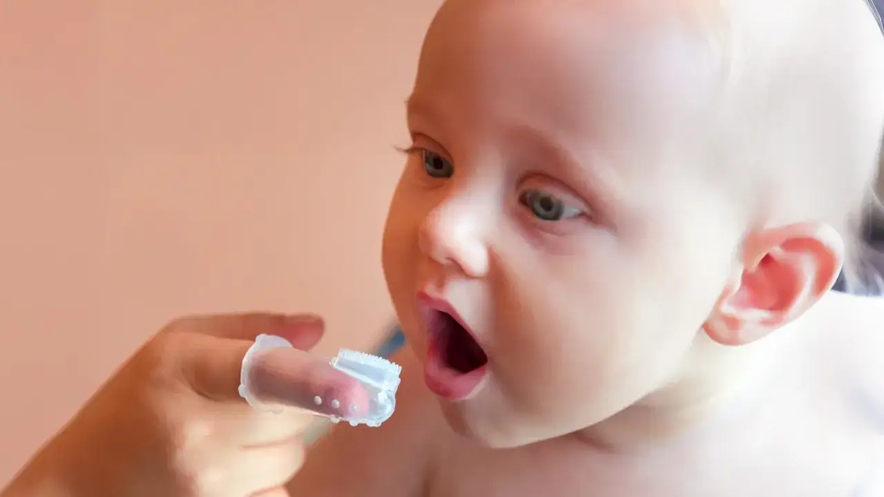 Un neonato con ciuccio, o meglio, un dito con spazzolino per neonati pronto per la pulizia.