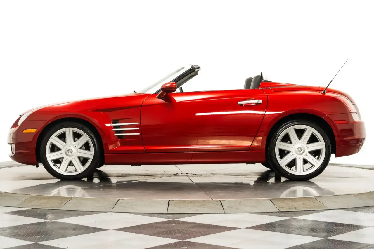Czerwony kabriolet Chrysler Crossfire auto na obrotowej platformie, z otwartym dachem i błyszczącym lakierem.
