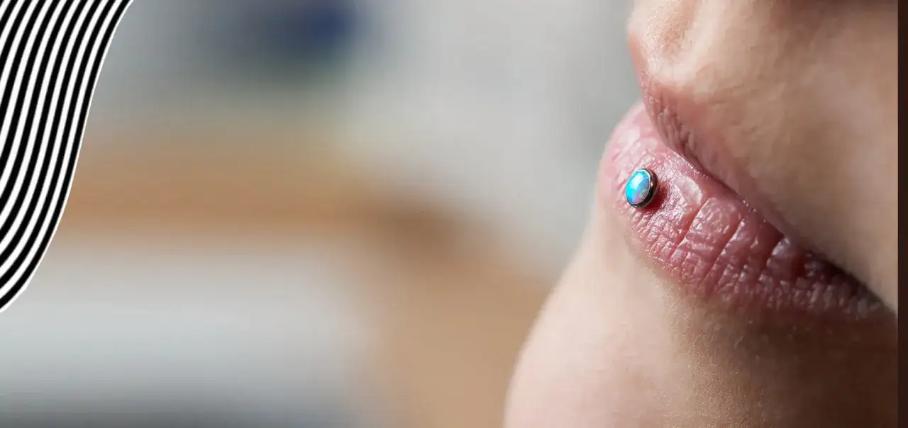 Zbliżenie na usta z błyszczącym, niebiesko-białym kamieniem w Ashley piercing.