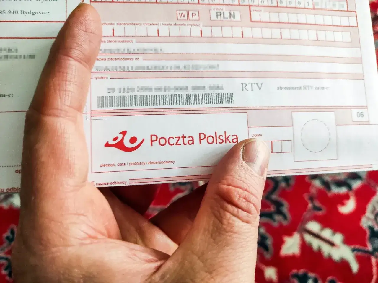 Dłoń trzyma druk Poczty Polskiej z polem