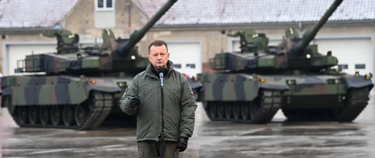 Mężczyzna w mundurze wojskowym przemawia przed czołgami. Dowiedz się, jak zostać kierowcą czołgu i dołączyć do wojska.