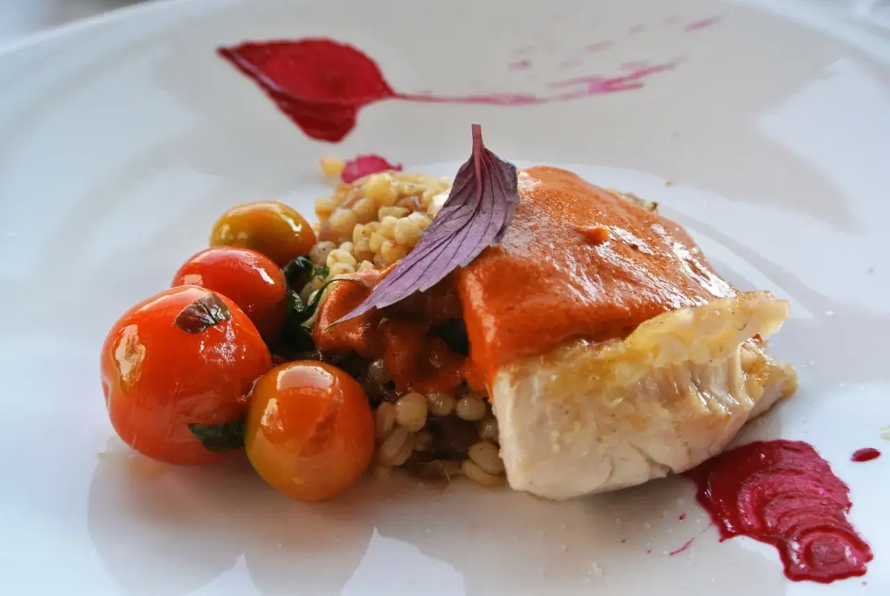 En vacker tallrik med chilensk mat: fiskfil&eacute; med r&ouml;d s&aring;s, k&ouml;rsb&auml;rstomater och korn.