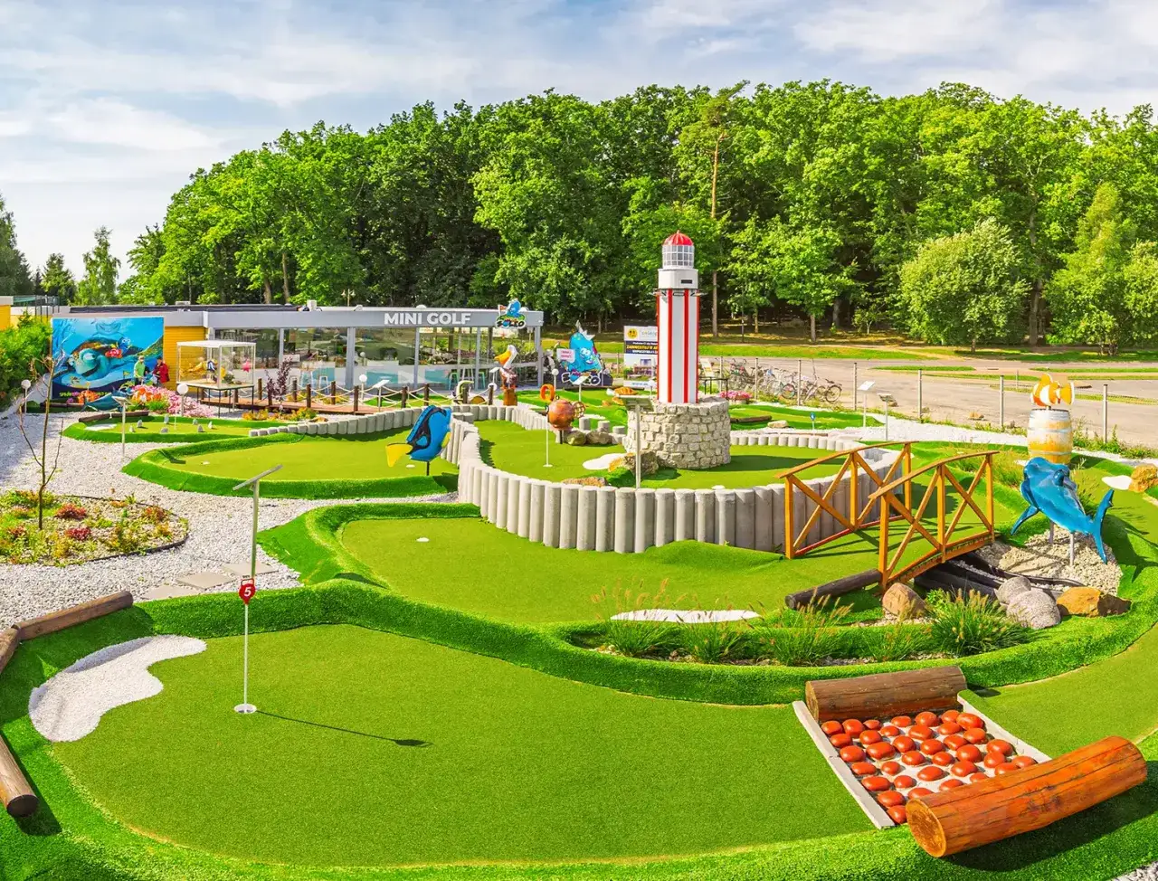Mini golf w Rewalu to świetne atrakcje dla dorosłych i dzieci. Wesołe figurki, mostek i latarnia morska tworzą wakacyjny klimat.