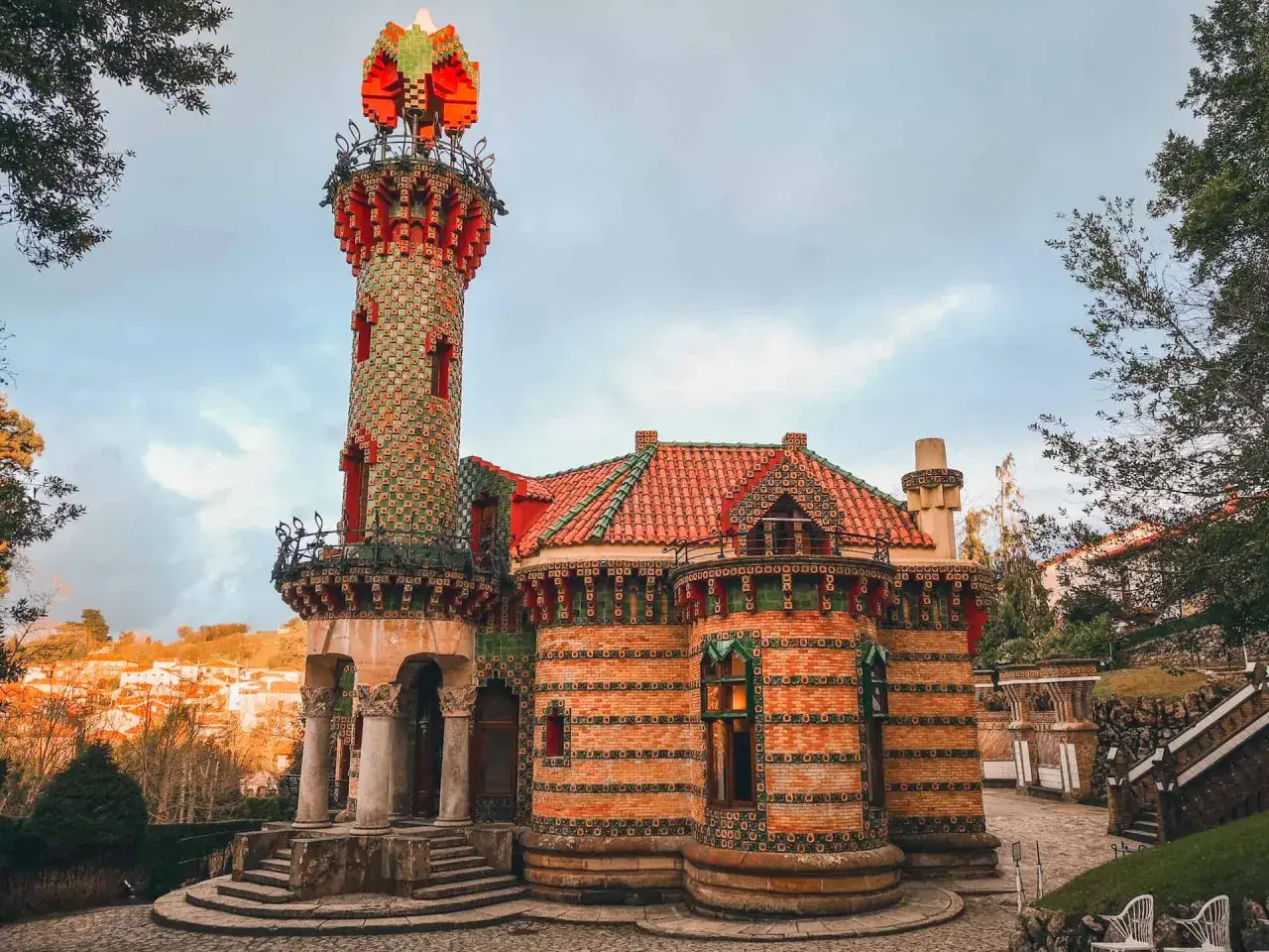 Edificio modernista con torre coronada por un capitel de cerámica roja y verde. Un lugar fascinante que ver en comillas, con detalles arquitectónicos únicos.