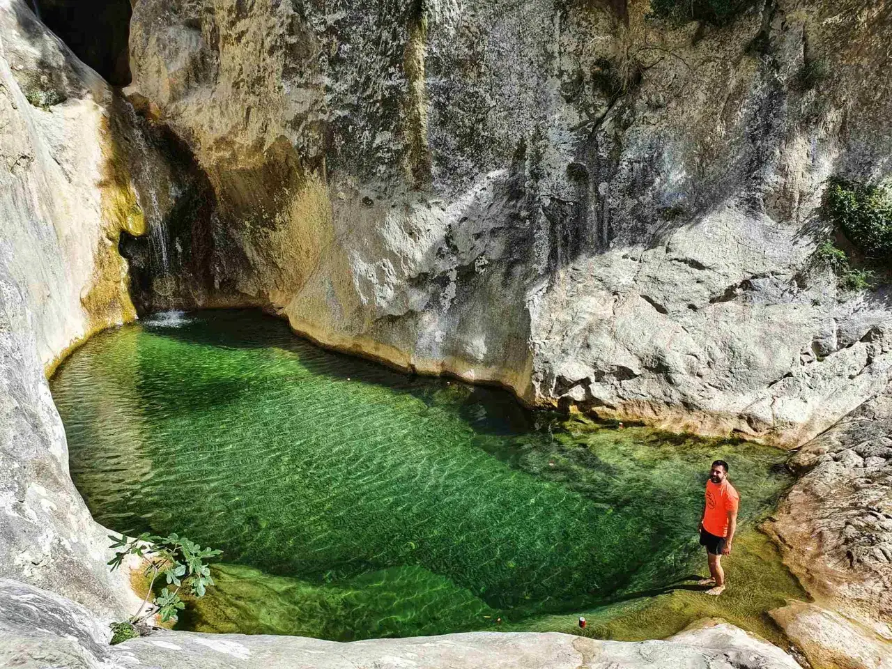 Un hombre se ba&ntilde;a en el **gorg blau Girona**, un oasis de aguas cristalinas rodeado de rocas y vegetaci&oacute;n.