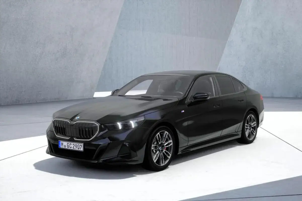 Elegancki, czarny sedan BMW 540d prezentuje się nowocześnie na tle betonowej architektury.
