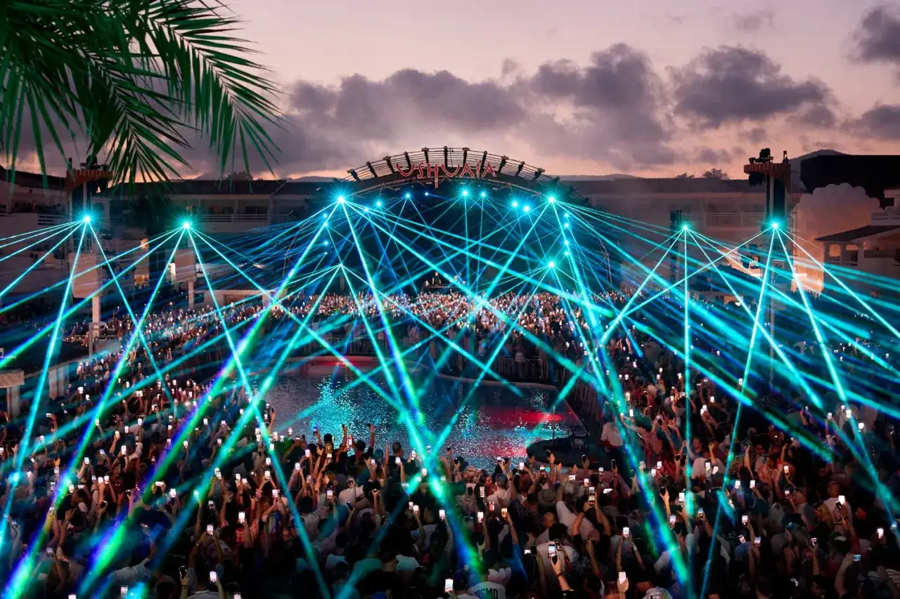 Un'incredibile line up a Ibiza, con migliaia di persone che alzano i cellulari sotto un cielo di laser blu e verdi.