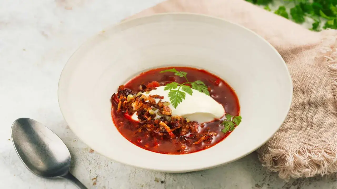 En sk&aring;l med r&ouml;d borsjtj, toppad med en klick gr&auml;ddfil och krispiga bitar. Ett perfekt borsjtj recept f&ouml;r en kall dag.
