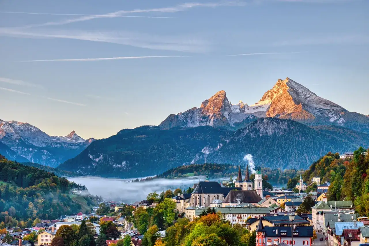 Morgendliche Nebelschwaden über Berchtesgaden, im Hintergrund der majestätische Watzmann, der wie ein kleiner Bruder über der Stadt thront.