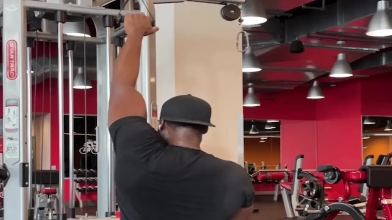 Man tränar enarms latsdrag på gym.