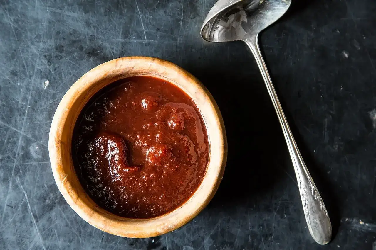 Eine Schüssel mit köstlicher Rotwein-Sauce, bereit zum Servieren. Daneben liegt eine elegante Schöpfkelle. Perfekt zum Rotwein kochen.