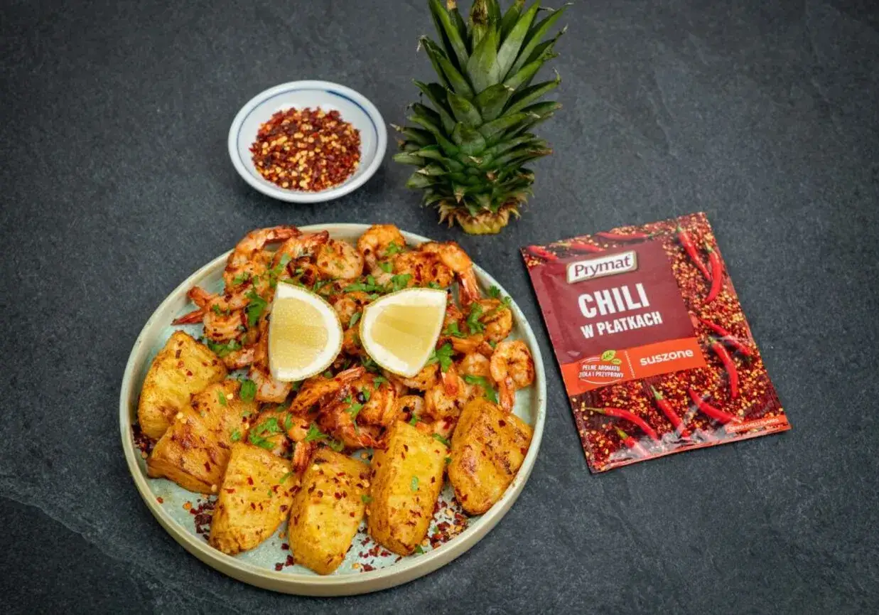 Krewetki z airfryer z ananasem i chili. Pikantne krewetki z airfryer, podane z grillowanymi kawałkami ananasa, cytryną i posypane płatkami chili.