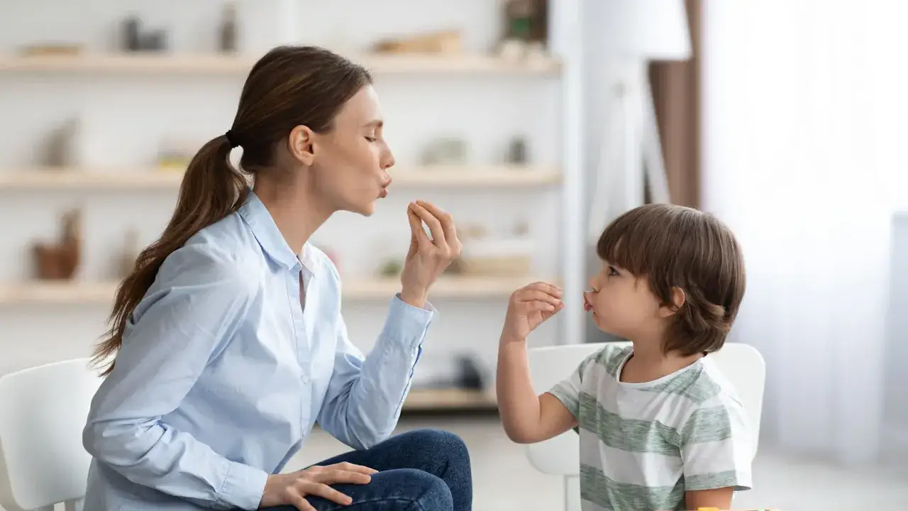 Therapeutin übt mit 4-jährigem Kind, um Autismus-Symptome zu erkennen. Sie machen Lippenbewegungen, um die Kommunikation zu fördern.