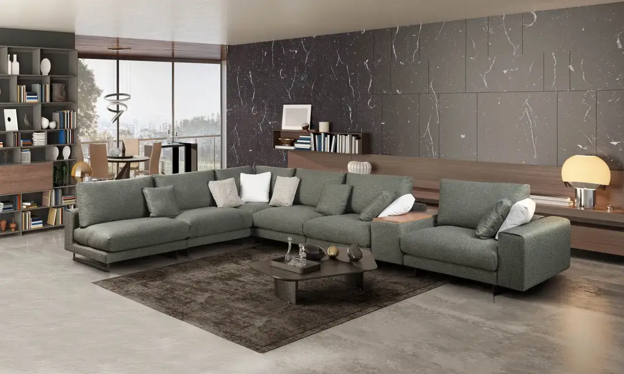 Elegante salón con sofá modular gris oscuro, alfombra oscura y pared de mármol.