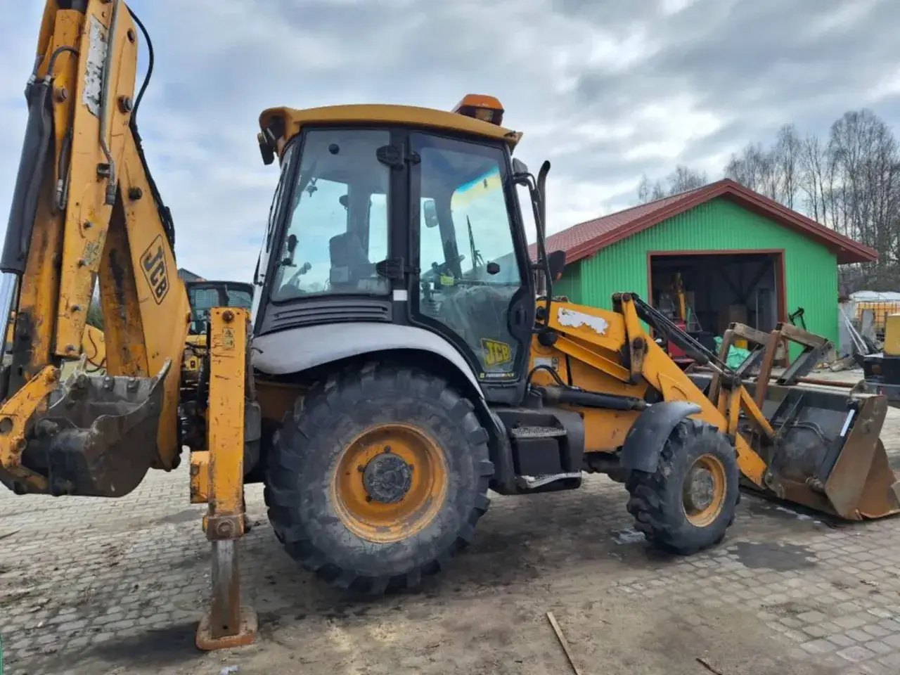 Nowa koparko ładowarka JCB gotowa do pracy. Potężna maszyna z żółtym osprzętem i kabiną czeka na nowe wyzwania.
