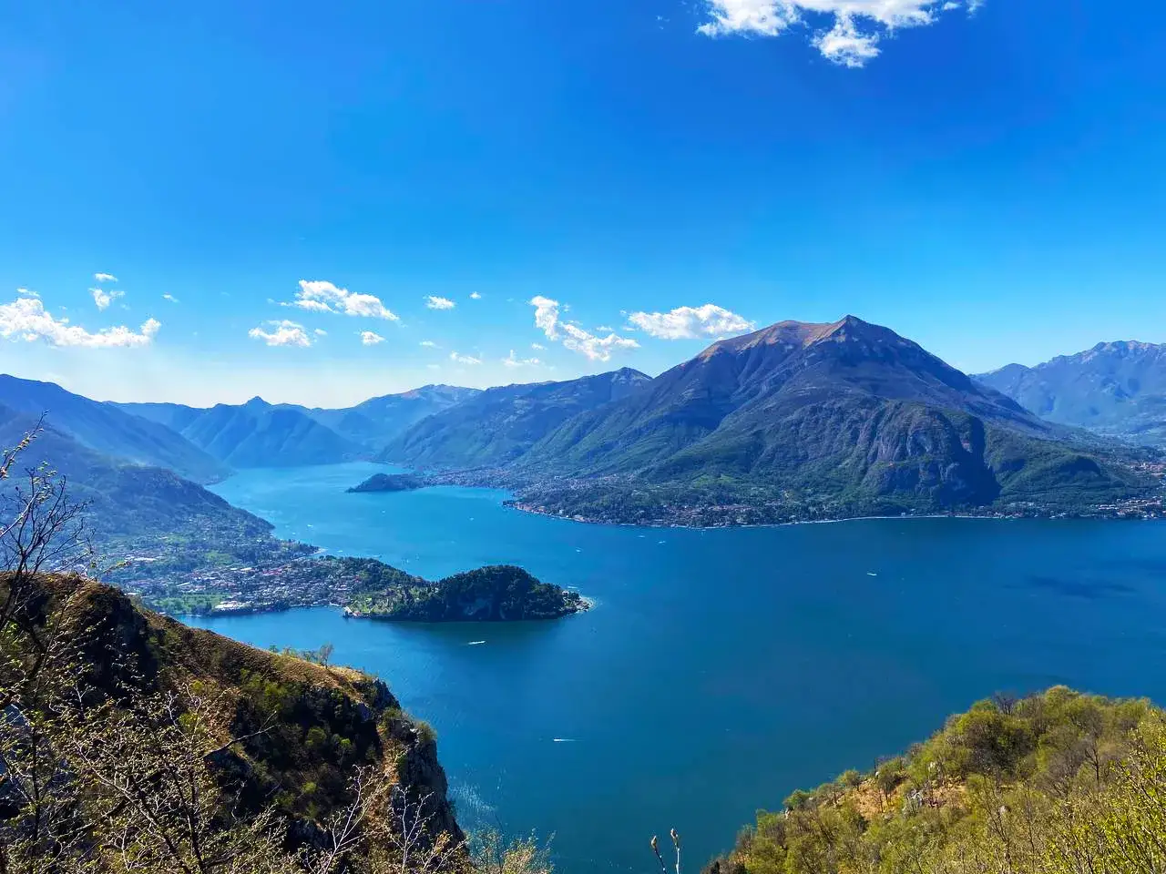 Panoramica mozzafiato del Lago di Como, con montagne verdi e un cielo azzurro. Ideale per esplorare le **sentiero del viandante tappe**.
