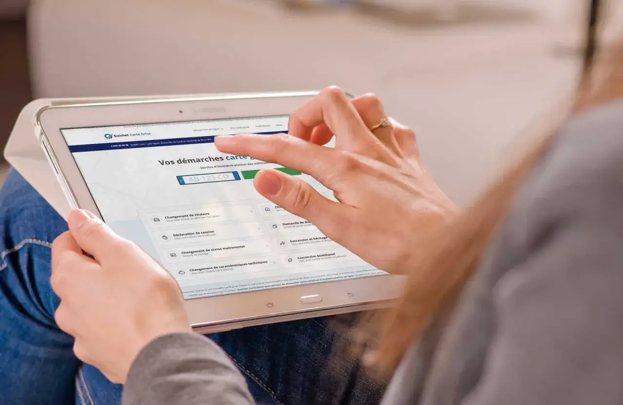 Une personne utilise une tablette pour effectuer des démarches en ligne, comme une demande de carte grise pour une voiture électrique.