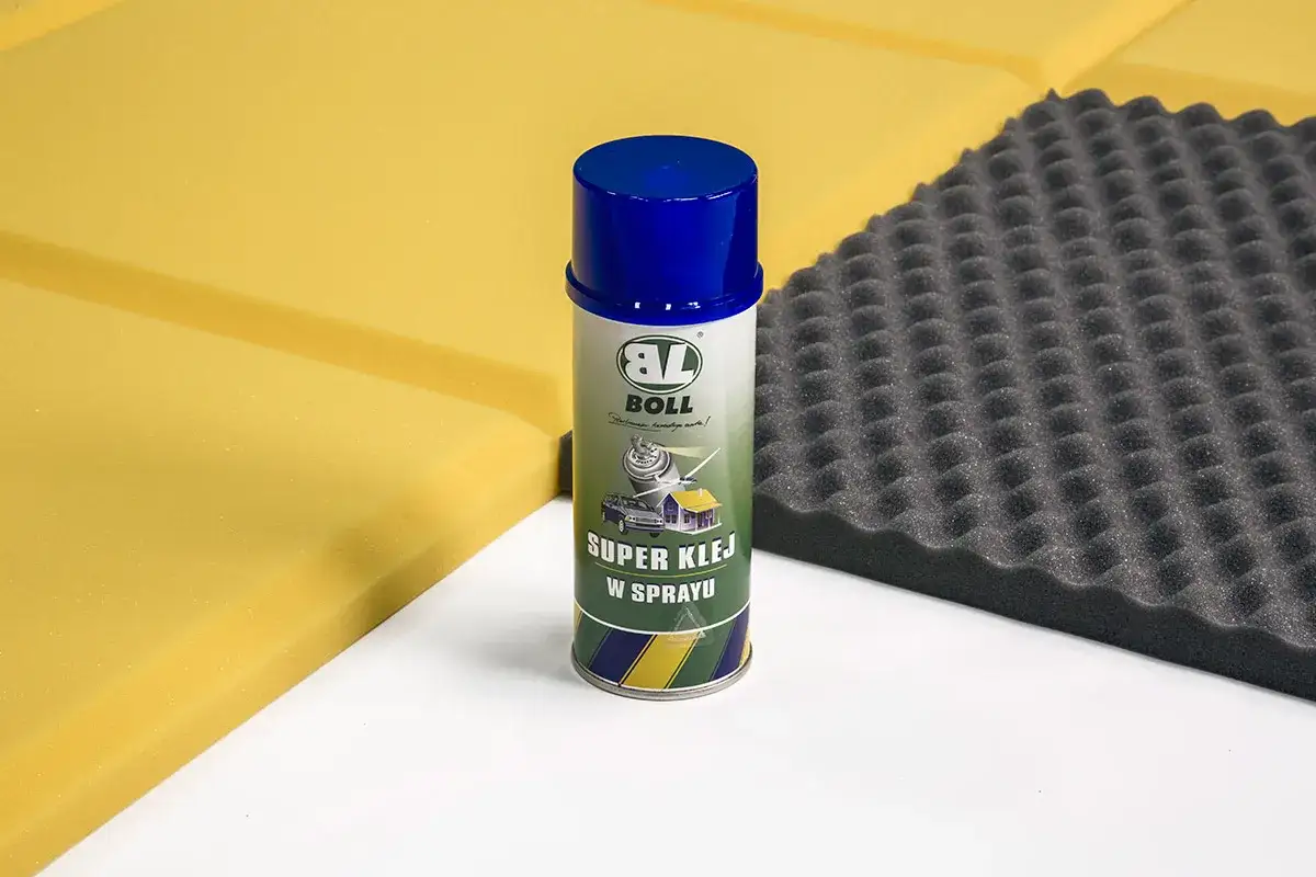 Puszka z super klejem w sprayu Boll obok żółtej i czarnej pianki akustycznej. Idealny do montażu elementów wygłuszających.