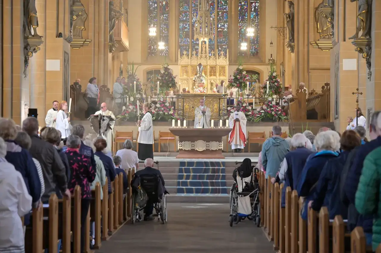 Gläubige in einer Kirche, wie beten Christen: Priester zelebrieren Gottesdienst vor buntem Altar, Menschen sitzen und stehen in den Bänken.