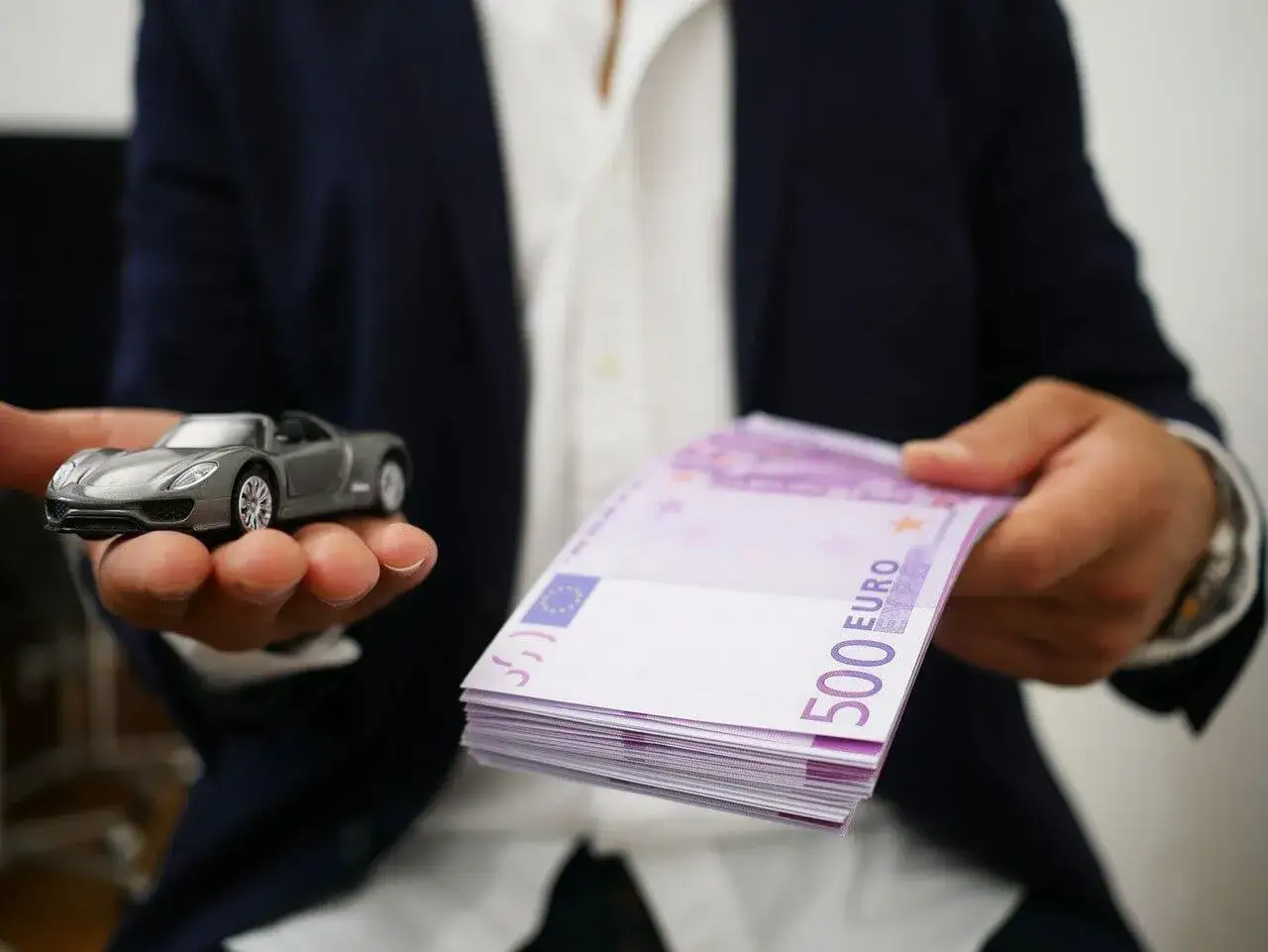 Model samochodu i stos banknotów 500 euro. Symbolizuje to cesję leasingu i transakcję finansową.