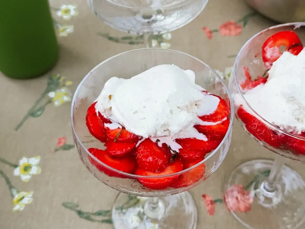 Två glas med limemarinerade jordgubbar och vaniljglass på ett blommigt duk.