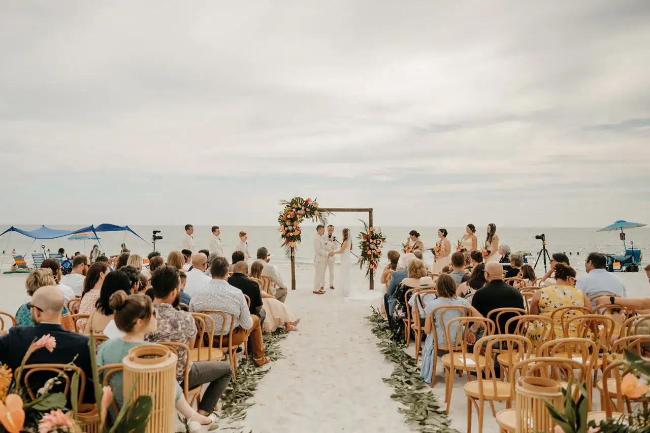 C&eacute;r&eacute;monie de mariage sur la plage, un couple &eacute;change ses v&oelig;ux sous une arche fleurie. Une belle id&eacute;e pour savoir o&ugrave; se marier &agrave; l'&eacute;tranger.