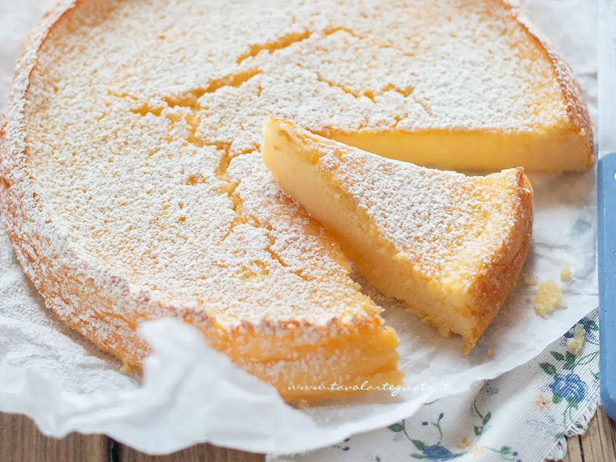 Una fetta di torta di ricotta soffice e dorata, cosparsa di zucchero a velo.