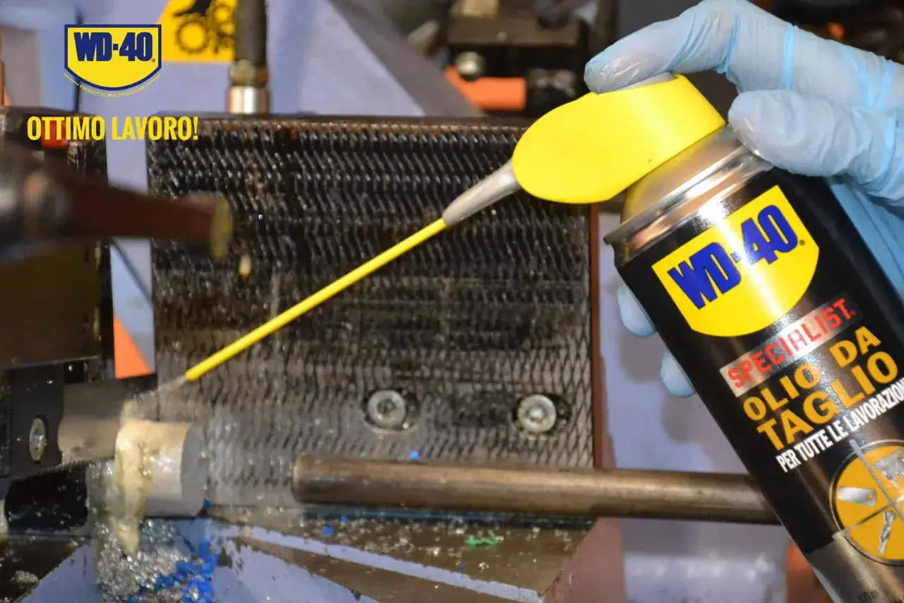 Mano con guanto blu spruzza olio da taglio WD-40 su un profilo in alluminio mentre viene tagliato. Ottimo lavoro!