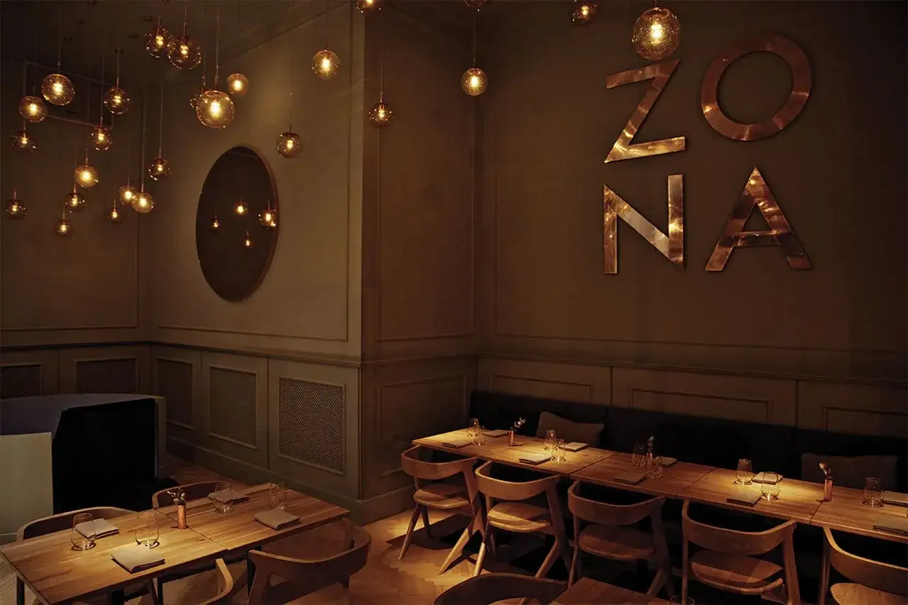Elegante diseño de iluminación para restaurantes, con lámparas colgantes doradas y el letrero